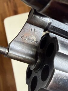 Close-up of a revolver frame with engraved markings: 'LW' and '21004' visible near the cylinder.